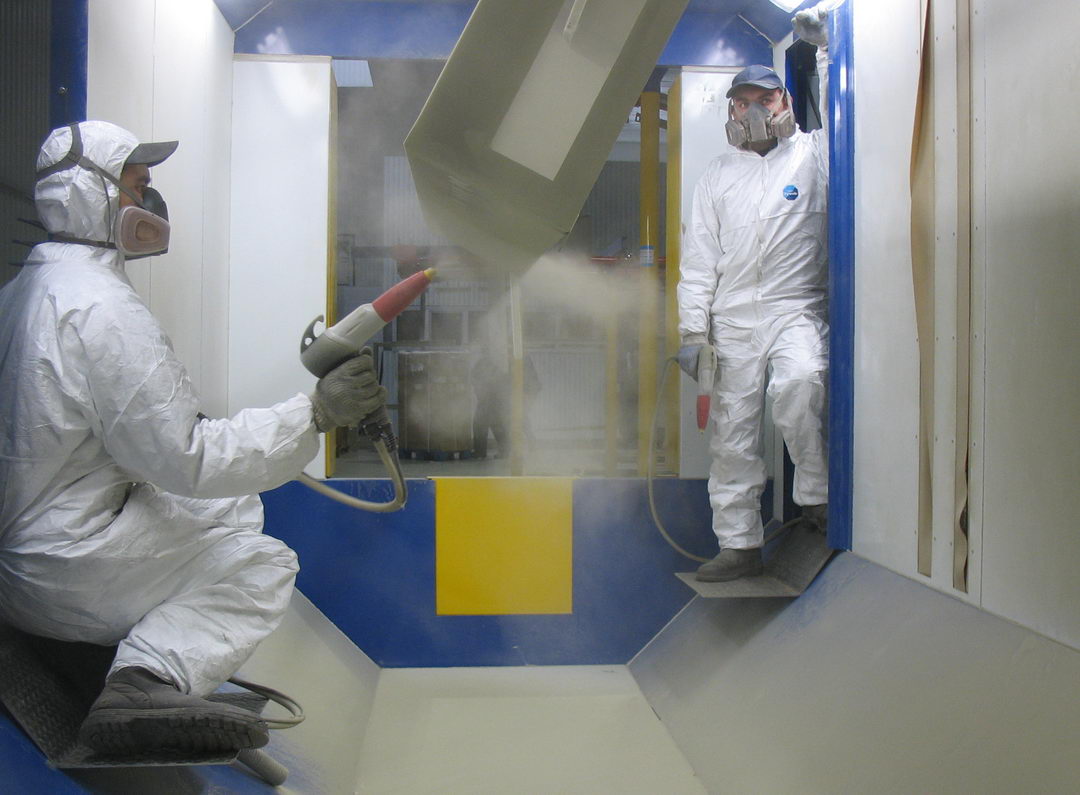 In the photo: manual powder coating on a conveyor line